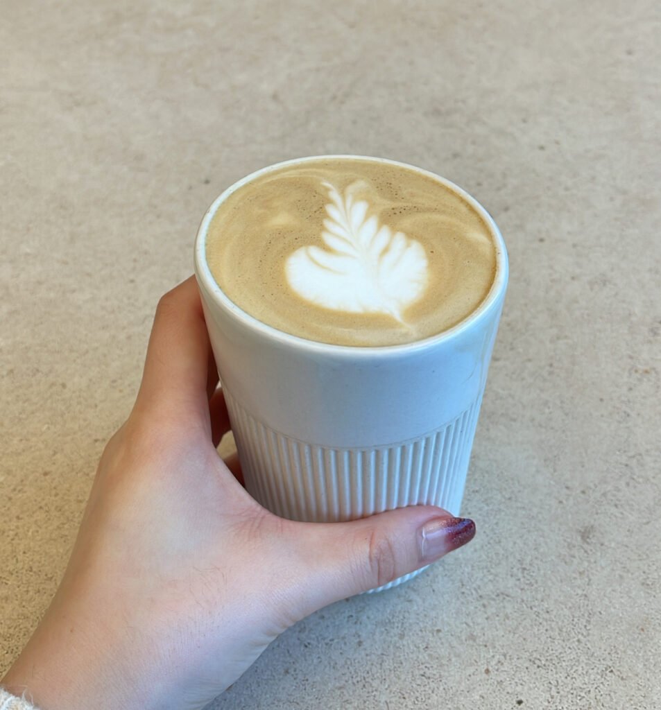 A woman is grabbing a cup of coffee.