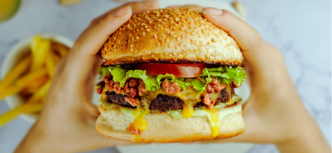 Unrecognizable person eating appetizing hamburger