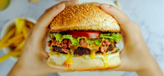 Unrecognizable person eating appetizing hamburger Unrecognizable person eating appetizing hamburger